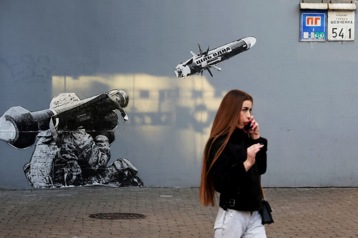 A woman walks by graffiti painted wall outside a coffee shop in Kyiv