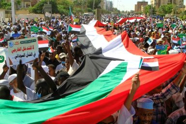 Sudanese protesters carry a giant national flag outside the UN headquarters in Khartoum on Saturday