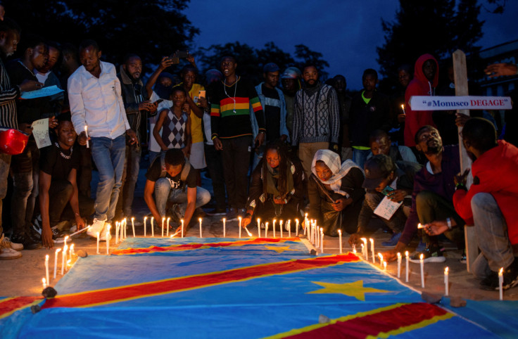 Congolese activists light candles on their national flag during a vigil in memory of the civilians killed in the recent conflict between FARDC and rebel forces, in Goma