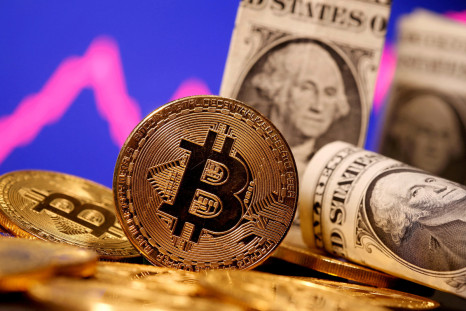 A representation of virtual currency Bitcoin and U.S. One Dollar banknotes are seen in front of a stock graph in this illustration