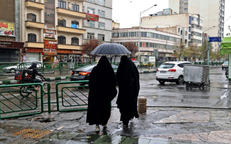 Women share an umbrella at Enghelab Square in Iran's capital Tehran on December 5, 2022