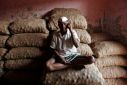 Labourer talks on his mobile phone as he sits on sacks of onions at a wholesale market in Mumbai
