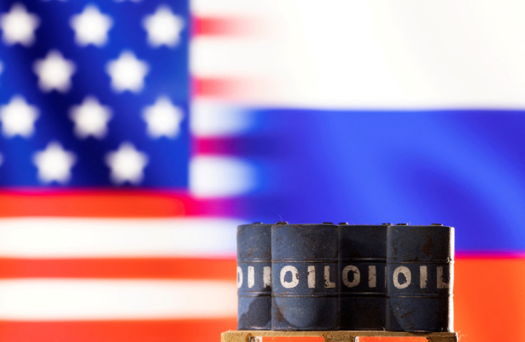 Illustration shows Models of oil barrels in front of sign U.S. and Russia flag colours