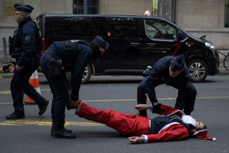 Police officers cart off  an activist dressed as Santa Claus outside the Ecological transition ministry in Paris to denounce the government's environmental policy on the eve in Montreal of the COP15 biodiversity summit on December 6, 2022