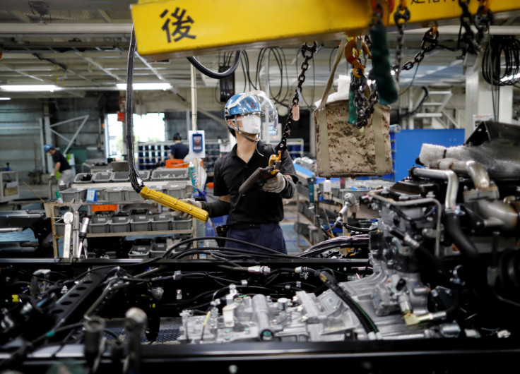An employee wearing a protective face mask and face guard works on the automobile assembly line at the factory of Mitsubishi Fuso Truck and Bus Corp in Kawasaki