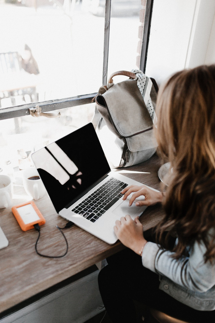 Woman Sitting Beside Table While Using Macbook