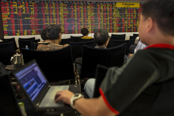 Thai investors sit in front of electronic board displaying live market data at stock broker's office in central Bangkok