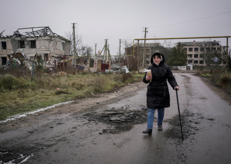 Local resident Oksana Oliinyk holds bread as she walks near destroyed buildings in the village of Posad-Pokrovske