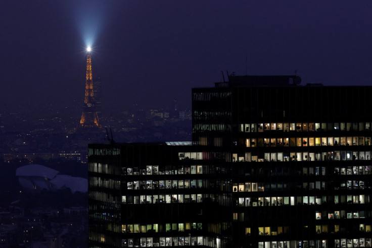 The Eiffel Tower lights the sky behind La Defense business and financial district near Paris