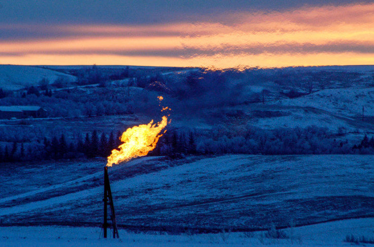 A natural gas flare on an oil well pad burns as the sun sets outside Watford City, North Dakota