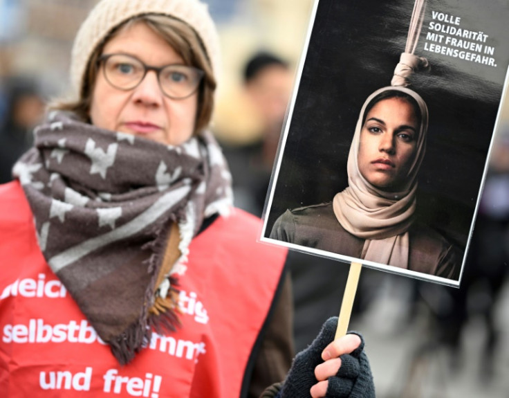 A demonstrator in Berlin holds a poster in solidarity with 'women in danger of death,' after Iran carried out its first execution linked to the protests in the Islamic republic