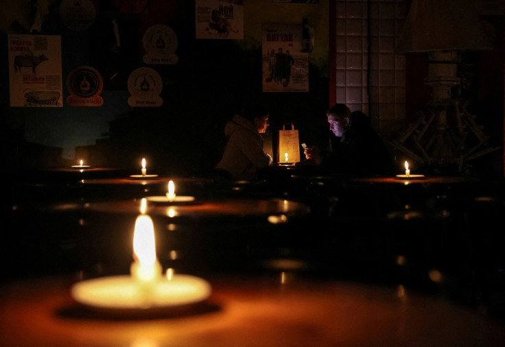 People sit in a pub lit with candles during a power outage after critical civil infrastructure was hit by Russian missile attacks in Lviv