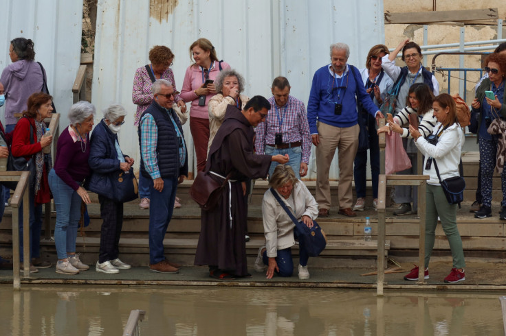 A religious person sprays a woman with Jordan River water at the Qasr el-Yahud site, near Jericho, in the Israeli-occupied West Bank, as pictured from the Jordan Valley