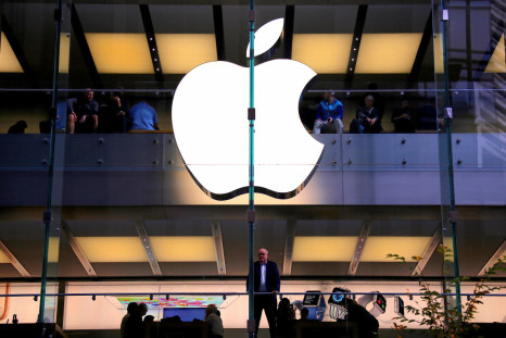 A customer stands underneath an illuminated Apple logo as he looks out the window of the Apple store located in central Sydney
