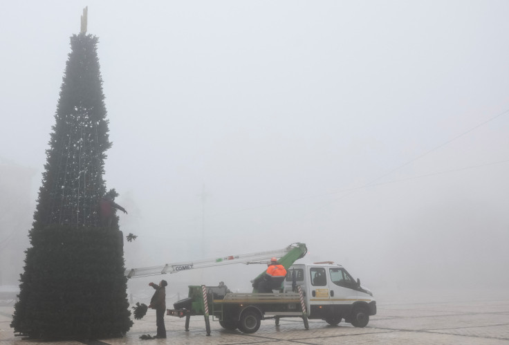 Municipal workers install a Christmas tree during a heavy fog at the Sofiyska square in Kyiv