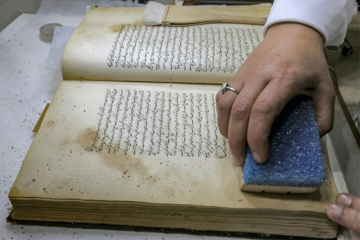 A conservator uses a sponge on a Persian-language manuscript undergoing restoration at the House of Manuscripts in Baghdad