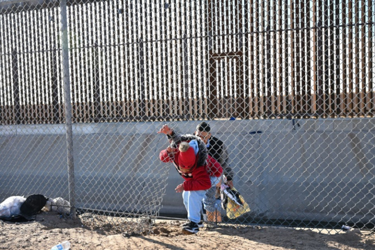 A family of migrants from Colombia climbs through a  fence along the US-Mexico border in El Paso, Texas, where new arrivals have surged amid a possible lifting of restrctions that have essentially shut the border for two years