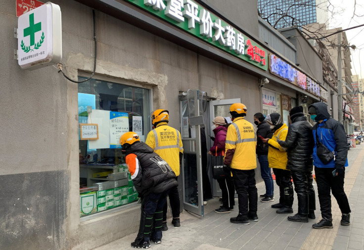 Delivery workers wait outside a pharmacy to pick up orders as COVID-19 outbreaks continue in Beijing
