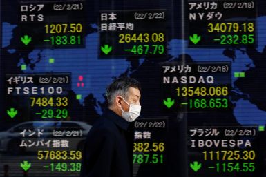 A man wearing a protective mask, amid the coronavirus disease (COVID-19) outbreak, walks past an electronic board displaying Japan's Nikkei index and various countries' stock market index prices outside a brokerage in Tokyo