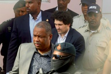 FTX founder Sam Bankman-Fried (C) handcuffed and escorted by law enforcement at a Nassau, Bahamas court