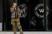 A man wearing military camouflage stands at the entrance of the 'PMC Wagner Center,' associated with the founder of the Wagner private military group Yevgeny Prigozhin, in St Petersburg
