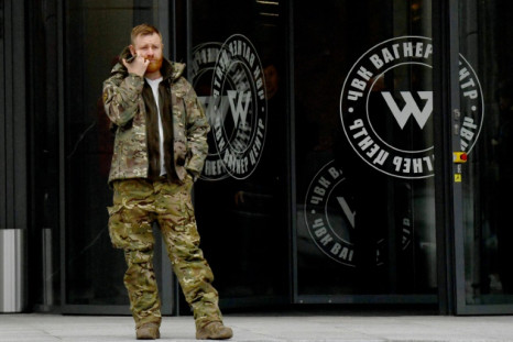 A man wearing military camouflage stands at the entrance of the 'PMC Wagner Center,' associated with the founder of the Wagner private military group Yevgeny Prigozhin, in St Petersburg