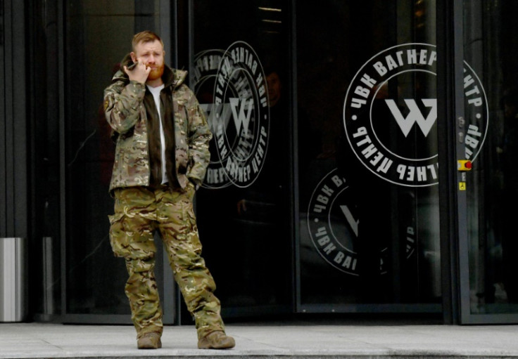 A man wearing military camouflage stands at the entrance of the 'PMC Wagner Center,' associated with the founder of the Wagner private military group Yevgeny Prigozhin, in St Petersburg