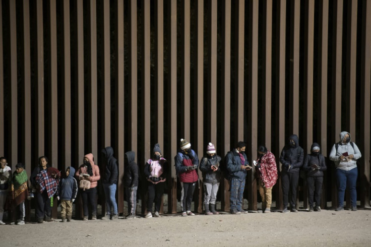 Asylum-seekers line up to be processed by US border agents at a gap in the US-Mexico border fence near Somerton, Arizona, on December 26, 2022