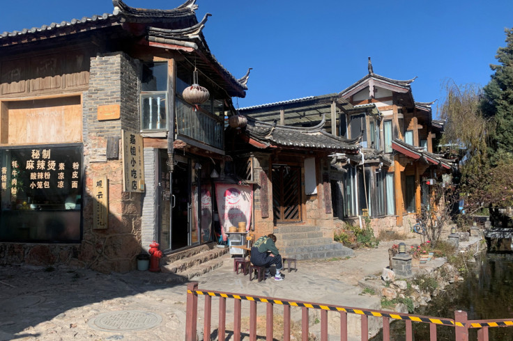 Man sits outside a restaurant at a tourist attraction in Lijiang