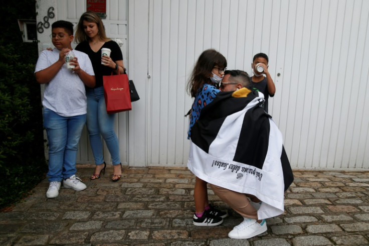 A Pele fan wrapped in a Santos flag embraces a girl in front of the Albert Einstein Israelite Hospital where Pele died