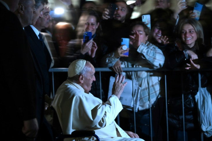 Pope Francis waves to onlookers while being pushed in a wheelchair through St Peter's Square on December 31