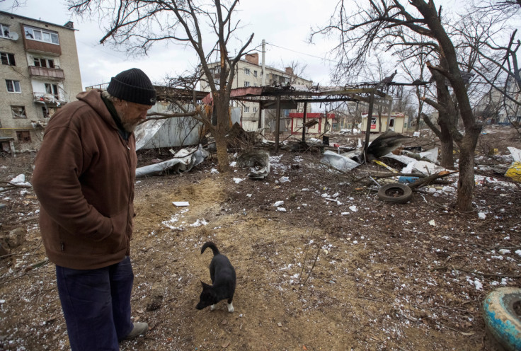 A local resident walks with a dog in a yard of his damaged apartment building in Bakhmut