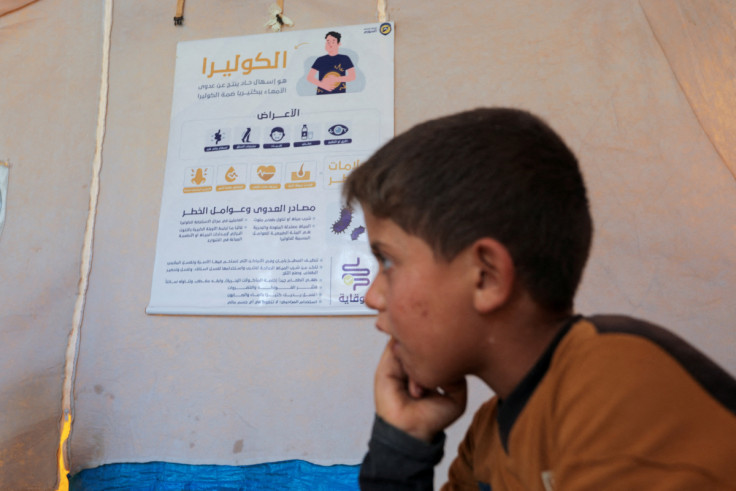An internally displaced boy listens to civil defense members during a cholera awareness campaign, at a camp in northern rebel-held Idlib
