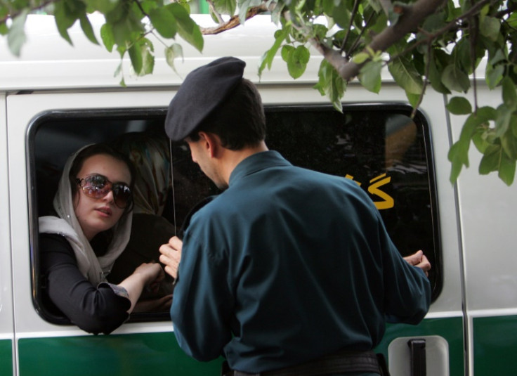 An Iranian police officer speaks with a woman arrested because of her allegedly inappropriate clothing in Tehran on July 23, 2007
