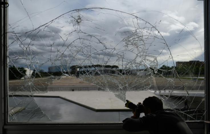 A journalist takes pictures of a broken window at the Planalto Palace in Brasilia, Brazil, on January 9, 2023, a day after supporters of Brazil's far-right ex-president Jair Bolsonaro invaded Congress, the presidential palace, and the Supreme Court