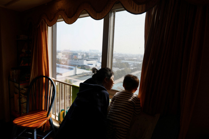 Ang Ran and her 2-year-old son Tang Ziang look out from their home in Beijing,