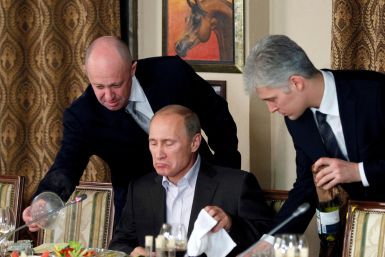 Yevgeny Prigozhin assists Russian Prime Minister Vladimir Putin during a dinner with foreign scholars and journalists at the restaurant Cheval Blanc on the premises of an equestrian complex outside Moscow
