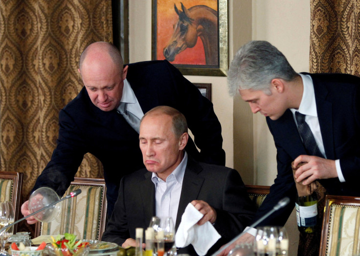 Yevgeny Prigozhin assists Russian Prime Minister Vladimir Putin during a dinner with foreign scholars and journalists at the restaurant Cheval Blanc on the premises of an equestrian complex outside Moscow