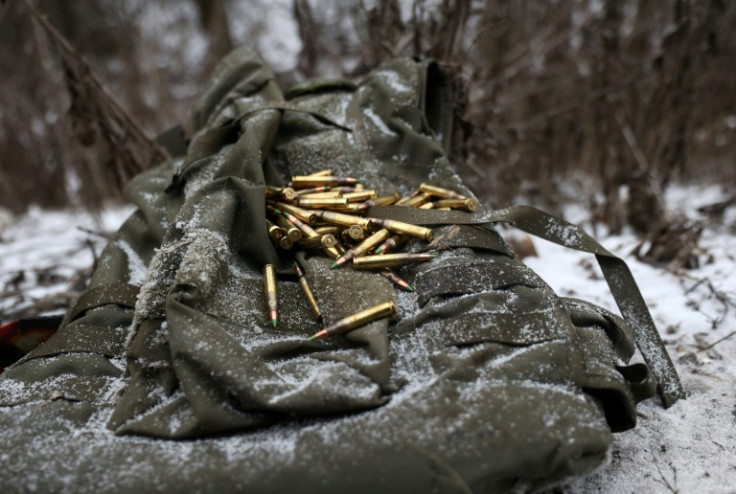 A medic kneels in the snow over one of the wounded's armoured vest, gathering cartridges and searching his identification documents