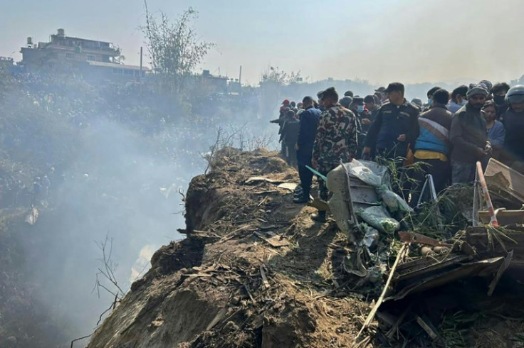 Rescuers and onlookers gather at the site of a plane crash in Pokhara, Nepal