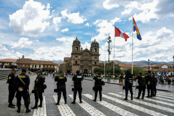Riot police stand guard at the Plaza de Armas in Cusco, Peru as residents carry out a rally for peace in memory of dozens who died in recent anti-government protests