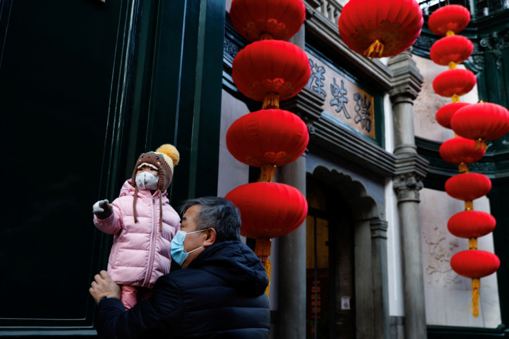 An elderly person holds a child near lanterns in Beijing