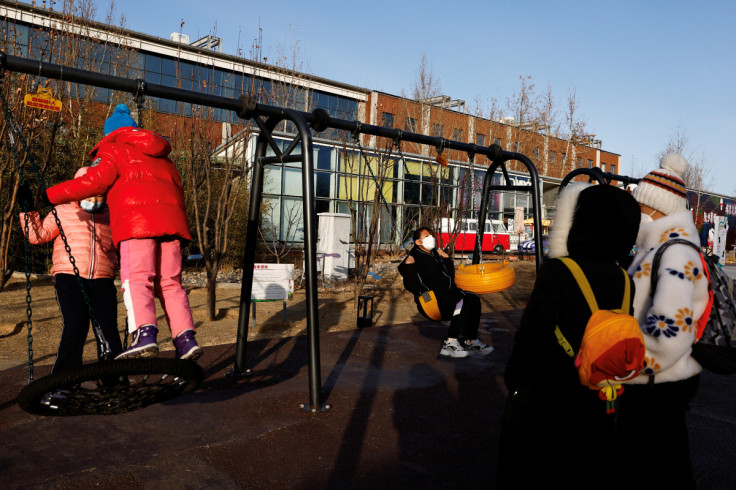 Children play on swings at a playground in Beijing