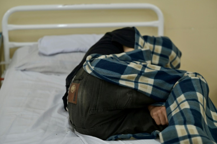 A drug addict at the Bicentenario public hospital in Guayaquil curls up in a blanket