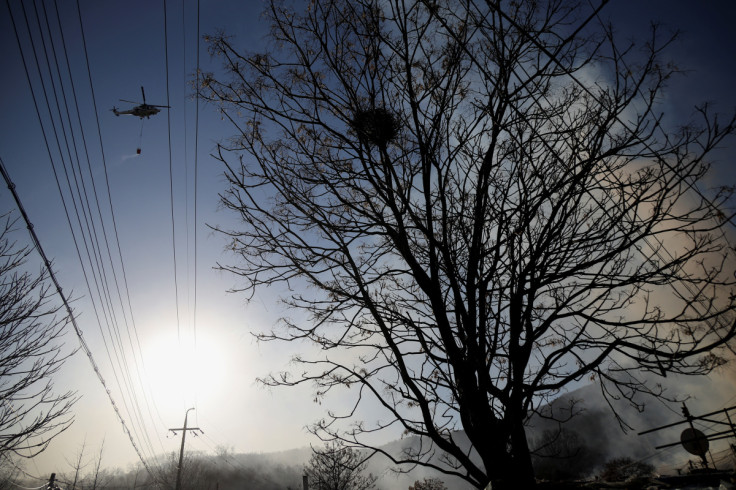 A helicopter arrives to splash water at the site of a fire at Guryong village, the last slum in the glitzy Gangnam district, in Seoul