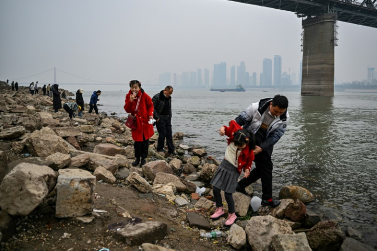 People stand on the banks of the Yangtze River in Wuhan on January 22