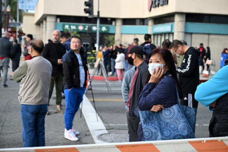Residents watch police investigate the scene of a mass shooting in Monterey Park, California, on January 22, 2023