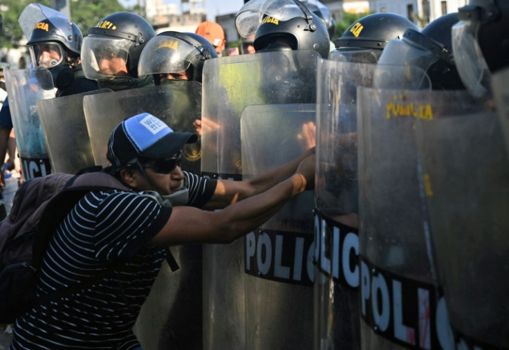 A demonstrator tussles with riot police in Lima