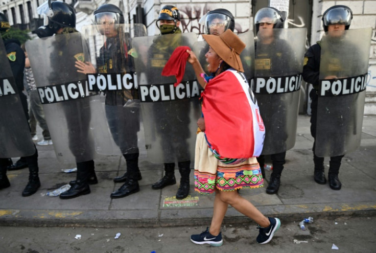 An indigenous woman walks in front of riot police during a protest in Lima on January 23, 2023