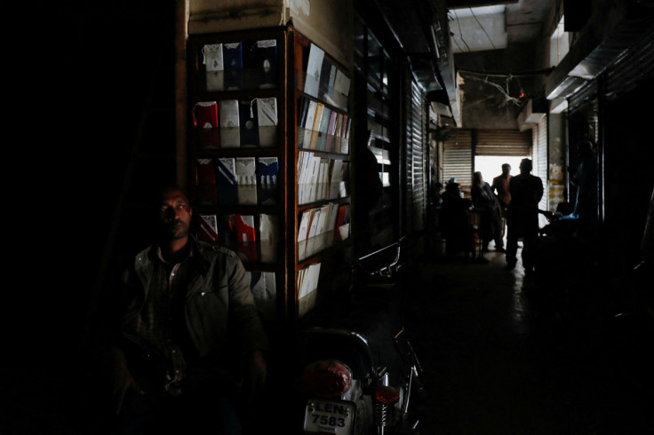 A man sits outside his shop during a country-wide power breakdown in Karachi